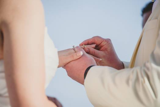 A groom places a wedding ring on the bride's finger, symbolizing their union during the ceremony.