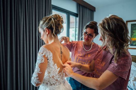 A bride is being helped into her wedding dress by two friends for a wedding at Koh Samui