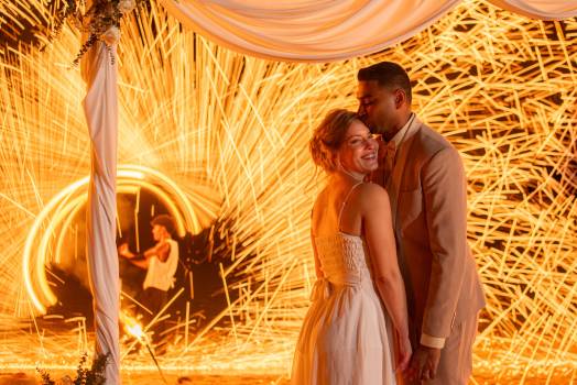 A happy couple stands together in front of a fireshow, creating a magical atmosphere.