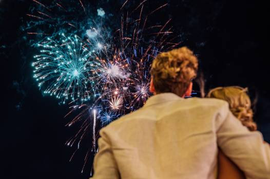 A couple enjoys a stunning fireworks display against a night sky, embracing each other in a moment of joy.