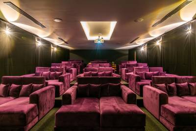 A cozy private cinema with plush purple seating and projector, creating a relaxed movie atmosphere.